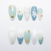 Beach-themed press-on nails with gold shell charms and sea green accents