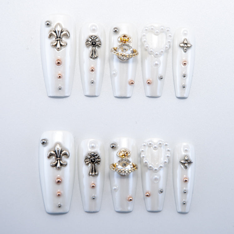 Handmade white nails with 3D pearl heart, cross, and royal emblem designs