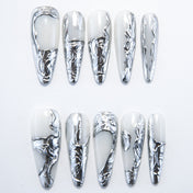 Handmade metallic nails with silver sculpted texture on a glossy white base