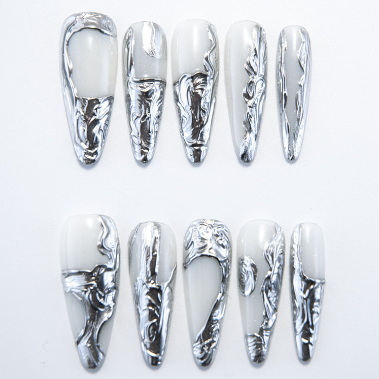 Handmade metallic nails with silver sculpted texture on a glossy white base