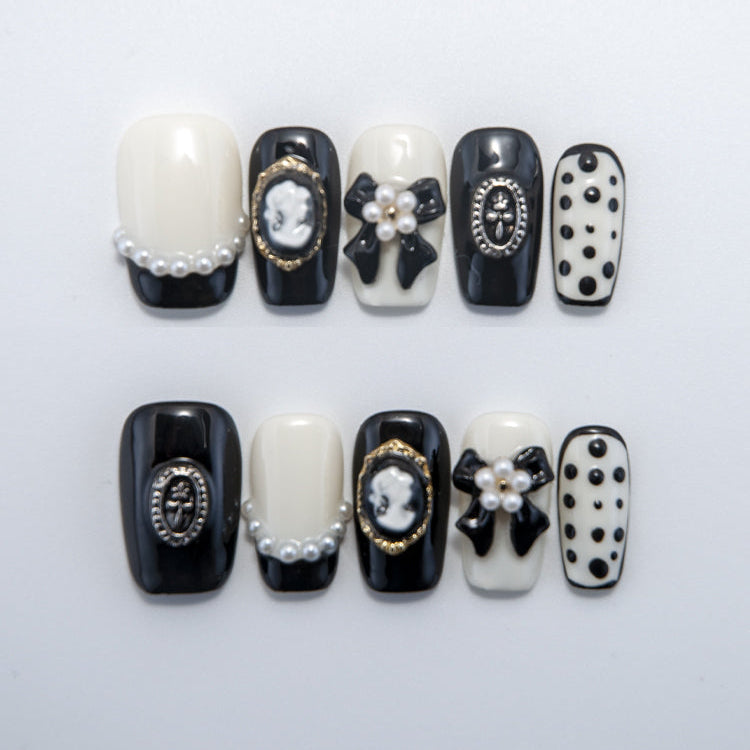 Black and white press-on nails with pearls, 3D bows, and vintage cameo charms