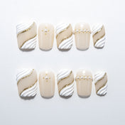 Ivory and white press-on nails with gold glitter waves and pearl accents