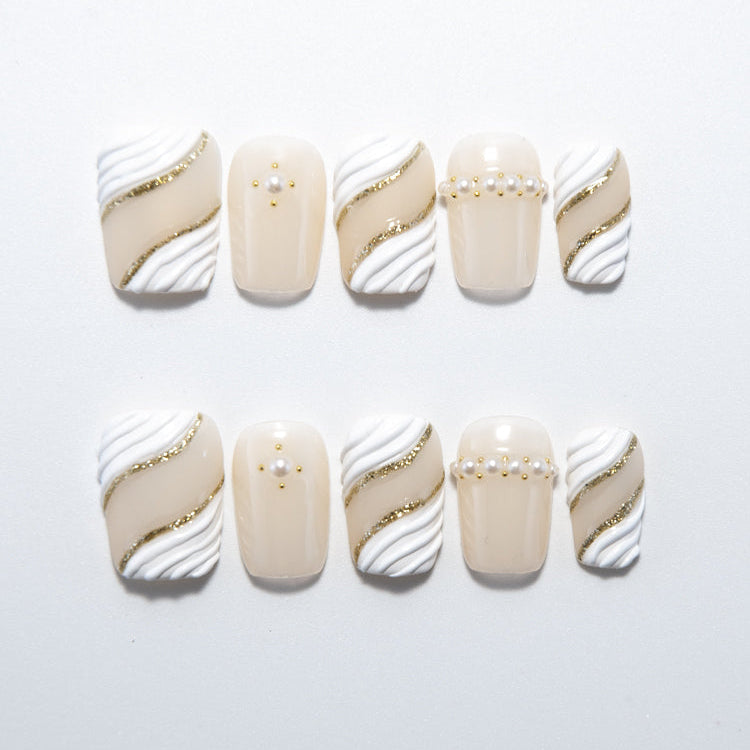 Ivory and white press-on nails with gold glitter waves and pearl accents