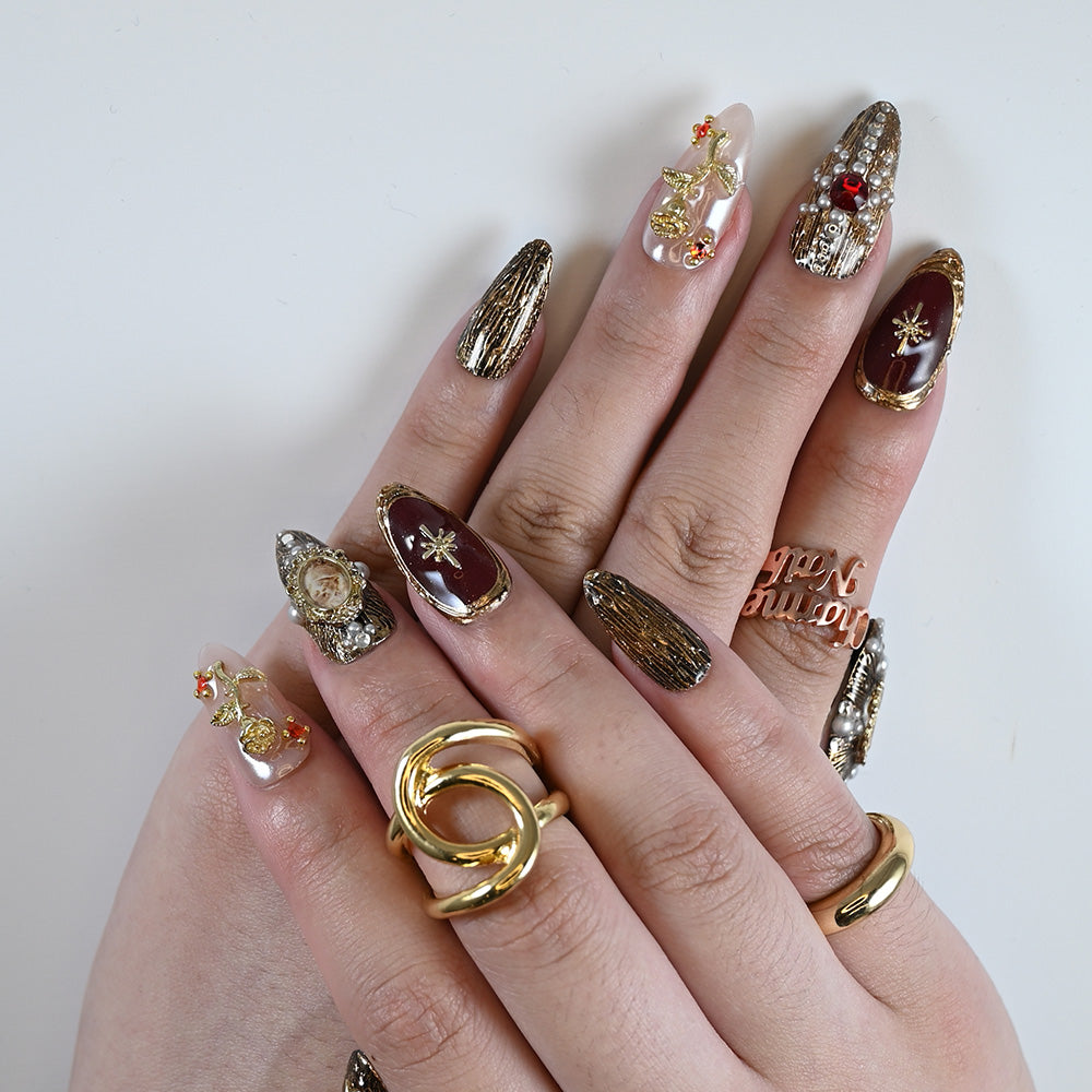 Gothic glam press-on nails with textured gold base, pearls, and ornate embellishments